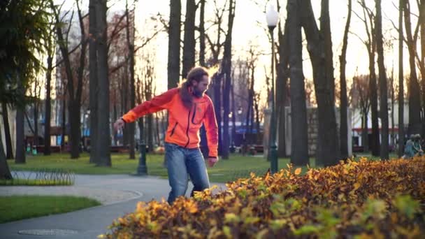 Un rodillo masculino profesional baila en patines en cámara lenta en un cómodo parque de la ciudad en los últimos días de otoño. Idea de actividades al aire libre y un estilo de vida saludable . — Vídeos de Stock