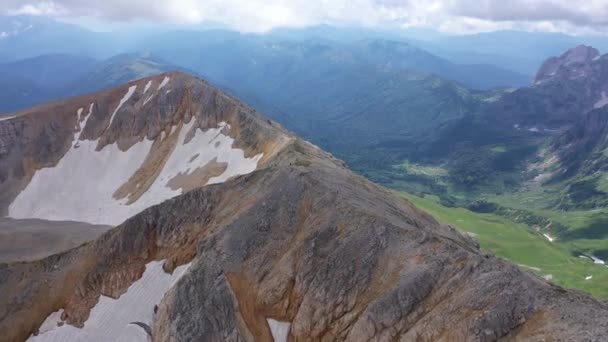 Aerial shot of a mountain ridge against rocky cliffs, glacier and snowy peaks. Amazing aerial view of a mountain landscape, Adygea, Russia. Aerial view of Mountain pass in Adygea, valley and mountain — Stock Video