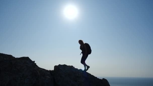 Genç kadın yavaş çekimde gün doğumunda zirveye doğru yokuş yukarı yürüyor. Güzel Kırım dağlarında yürüyüş yapan bir hanımın silueti güzel manzaranın ve vahşi doğanın tadını çıkarıyor. . — Stok video