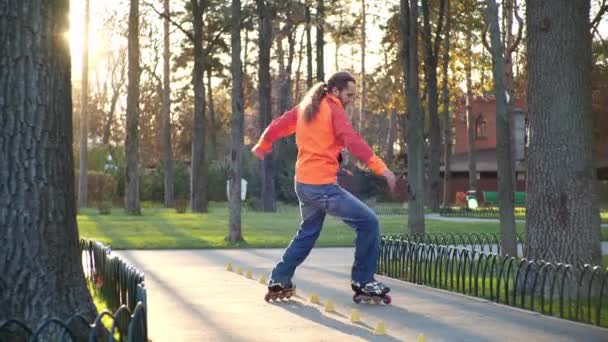 Profesjonalny łyżwiarz trenuje swoje umiejętności bypass między specjalnymi stożkami i robi skomplikowane zwroty techniczne. Roller skate trening w słonecznej pogodzie jesienią. Aktywny i wysportowany styl życia w zwolnionym tempie. — Wideo stockowe