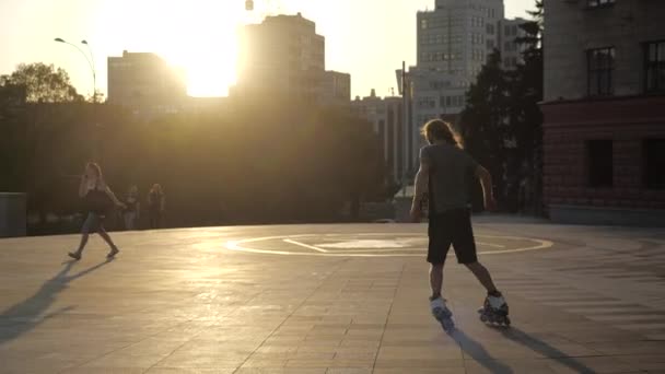 우크라이나 하르키우: 2019 년 10 월: 도시 공원의 화창 한 저녁 일몰에 긴 머리의 남자 롤러스케이트를 탔다. 롤러스케이트 탈락. — 비디오