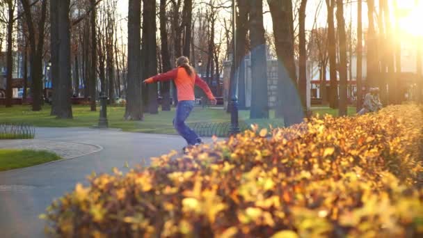 Een professionele mannelijke rolschaatser voert coole trucs en dansen uit op rolschaatsen in een comfortabel stadspark in de laatste dagen van de herfst. Idee van outdoor activiteiten en een gezonde levensstijl in een langzame — Stockvideo