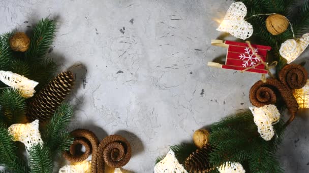 圣诞和新年的圣诞佳节装饰。 一双女性的手把绷带礼物放在桌上。 圆锥冷杉枝干坚果灯笼系在心形上. 慢动作 上图 — 图库视频影像