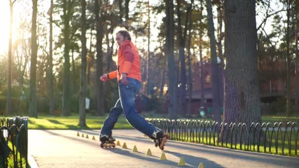 Życie sportowe na rolkach. Aktywny i wysportowany człowiek wykonuje profesjonalną technikę wrotkarską w chłodnym parku miejskim. Doświadczony rolkarz jeździ jesienią na świeżym powietrzu w parku w zwolnionym tempie. — Wideo stockowe