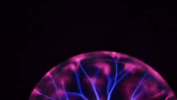 La bola de rayos de plasma se mueve al azar y se detiene en el centro sobre un fondo negro. Lámpara de descarga Tesla, globo de plasma con relámpago de alto voltaje. Tubo de descarga de gas inerte cambiando de color — Vídeo de stock