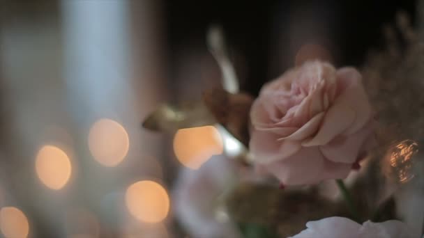 Beautiful fresh flowers in a vase in a close-up against the backdrop of flickering candles. White and pink roses prepared for the wedding. Flowers for the bride from the groom. Blurred glare of light. — 비디오