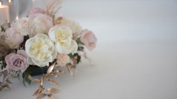 白と明るいピンクの色の結婚式のバラは、レジストリオフィスの花瓶にあります。光とキャンドルのぼやけてちらつきグレアの背景に美しい花。結婚式のための花. — ストック動画