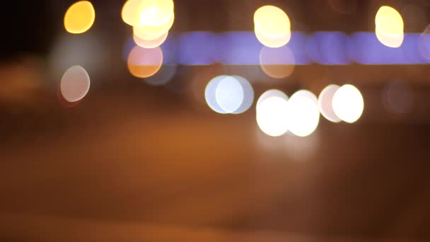 Pozadí pohybujícího se rozmazaného večerního světla města. Krásné třpytivé bokeh ve večerní tmě rozmazané pozadí v noci. Kulaté barevné bokeh lesk z pohybujících se světel aut v noci městské dopravy — Stock video