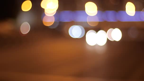 Fondo de mover las luces borrosas de la noche de una ciudad. Hermoso bokeh brillante en el fondo borroso oscuro de la noche por la noche. El bokeh colorido redondo brilla de las luces móviles del coche en el tráfico nocturno de la ciudad — Vídeos de Stock