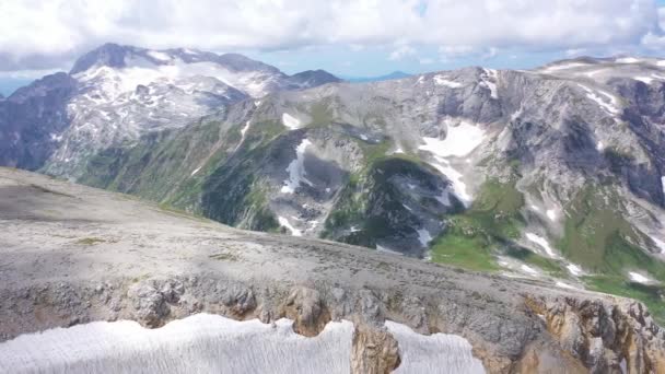 Zdjęcie lotnicze grzbietu górskiego na skalistych klifach, lodowcu i śnieżnych szczytach. Niesamowity widok z lotu ptaka, Adygea, Rosja. Widok z lotu ptaka z góry Dzika przyroda — Wideo stockowe