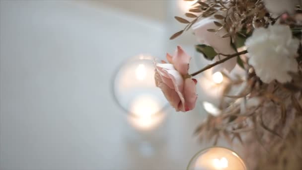 Pink-and-white flower hangs over glasses with candles, a top view in a dipped form. Romantic gift for a girl on any occasion. Wedding of the newlyweds. Cozy and warm atmosphere in the building. — Stockvideo