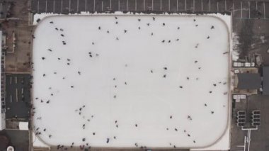 Kharkov, Ukrayna 'da bir buz pateni pistinde daireler çizen insanların hava görüntüsü. İnsanlar bulutlu bir günde paten sahasında kayarlar. İnsanlar güneşli bir günde buz pateni pistinde kayıyorlar. Dikey yukarıdan aşağı görünümün üzerinde.