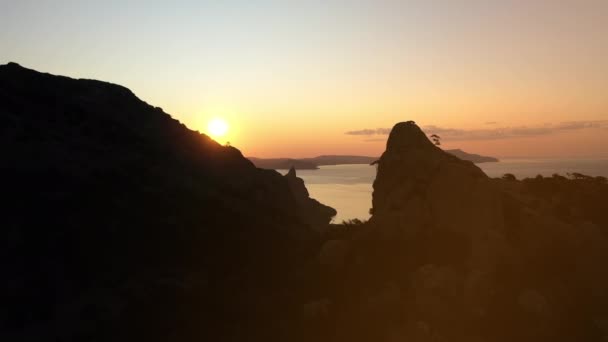 La prise de vue aérienne approchant de la mer Noire de la montagne Karaul-Oba, d'où le soleil jaune scintille dans la baie du soir. Une attraction touristique populaire. L'une des principales attractions de la Crimée . — Video