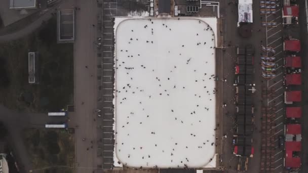 Kreisförmige Luftaufnahme einer Eisbahn im Stadtzentrum an der frischen Luft mit Menschen, die darauf in der Stadt Charkow, Ukraine, reiten. Feiertage im neuen Jahr und Weihnachtsferien. — Stockvideo