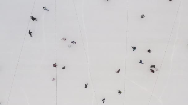 Blick von oben auf Menschen, die an der frischen Luft in der Innenstadt auf dem Eis einer Eisbahn rutschen. die Idee sportlicher Aktivitäten für das neue Jahr und Weihnachten. Schlittschuhlaufen in Charkow, Ukraine. — Stockvideo