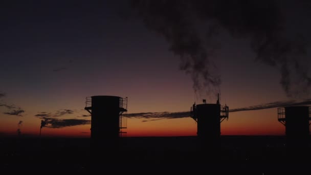 Kjelerom i kveldsbyen med solnedgangbakgrunn. Kraftig røyk kommer fra skorsteinene og stiger høyt. Miljøforurensning. Landets industri. Flere kjøletårn skytes fra toppen . – stockvideo