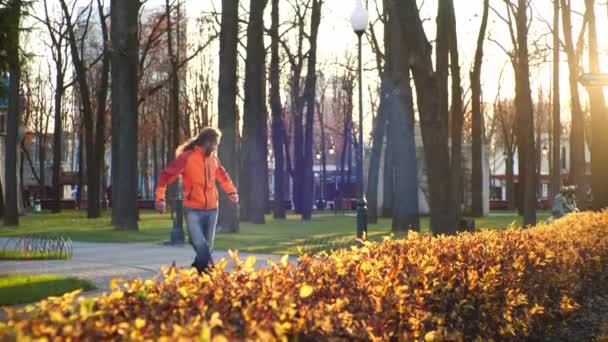 Paten kayan sporcu kaykaycı ve paten üzerinde antrenman yapan, güneşli bir sonbahar şehir parkının arka planında yavaş çekimde çeşitli numaralar ve unsurlar sergileyen. Faydalı bir yaşam biçimi. — Stok video