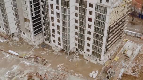 Vue de dessus du bâtiment de plusieurs étages actuellement en construction dans la ville de Kharkov, en Ukraine. Vue aérienne d'un immeuble de grande hauteur et d'un chantier de construction. Grues pour la construction d'un bâtiment — Video