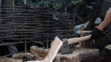 Balta ile çalışan insanların elleri. Adam açık havada ağır çekimde odun kesiyor. Bir oduncu odun için ağaç gövdelerini baltayla keser..