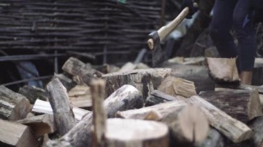 Adam yavaş çekimde açık havada odun doğrar. Baltayla çalışan erkek elleri. Bir adam oduncu odun için bir balta ile ağaç gövdeleri doğrar.