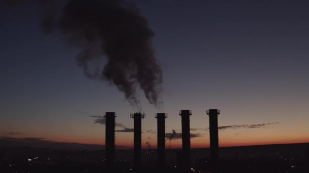 Dichter Rauch steigt auf. Umweltverschmutzung durch Schlote. Silhouette aus fünf Pfeifen. wunderschöner Sonnenuntergang über einem rauchenden Wärmekraftwerk. Sonnenuntergang über Kühltürmen und Schornsteinen. — Stockvideo