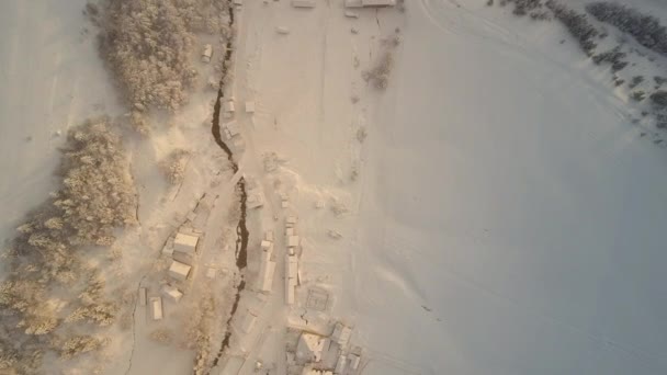 Piccola città accogliente coperta di neve in inverno con tempo soleggiato da una vista a volo d'uccello da qualche parte nei Carpazi, Ucraina. Territorio in montagna, cosparso di neve. Case nella neve bianca . — Video Stock