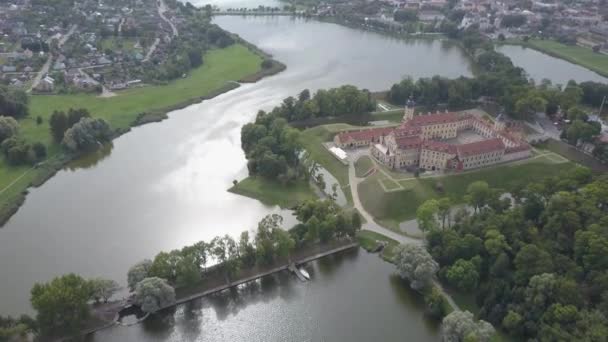 Flygfoto av den berömda Nesvizh slott i soligt väder, som ligger i den gamla staden Nesvizh i Vitryssland. Det vackra slottet är omgivet av parker och sjöar. Mästerverk i arkitektur ovanifrån. — Stockvideo