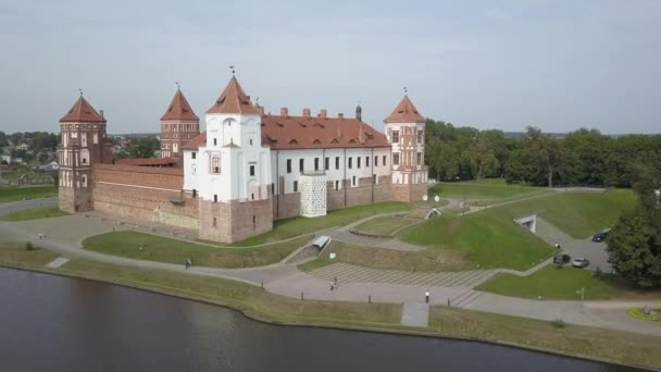 Amazing drone shot from above the famous Mir Castle in the village of Mir, Belarus. The ancient castle with five towers has a great history. Mir Castle by the lake and park, top view in slow motion. — Stok video