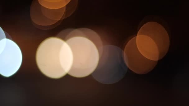 Belles lumières claires et floues sur un fond de rue sombre. Multi-coloré divers éblouissement de la lumière dans le tir flou. Éblouissement clignotant de lumière jaune, orange et bleue dans l'obscurité dans la soirée .
