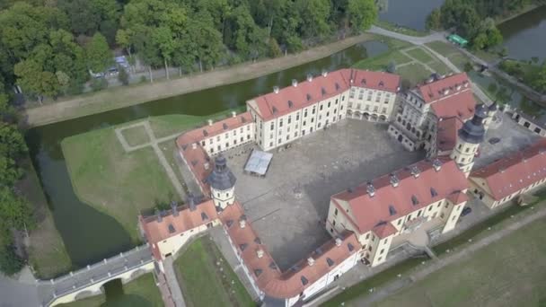 Nesvizh castle from a birds eye view on a sunny autumn day. The famous castle in the old town of Nesvizh in Belarus. The castle is surrounded by various lakes and parks with trees. Historic building. — стокове відео