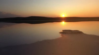 Kayashsky lake in Crimea, Ukraine, shot by a drone from above against the background of the evening sunset. Salty, clean and mineral lake view from above in slow motion. Flight over reflecting water.