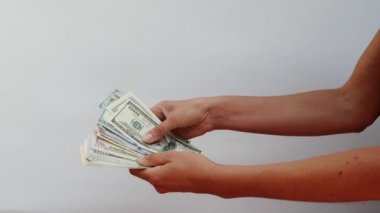 Female hands hold a wad of money and redefine them, close view on white background. Focus on womens hands, in which there are a lot of notes for 100 dollars and 50 euros. Girl recounts cash savings.