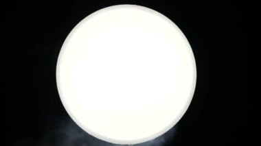 Close view of flying snow on a white ball in an isolated place. Small blizzard rushes along the snow-white circle against the background of absolute darkness. Feeling of cool winter and snowy days.