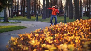 Paten kayan sporcu profesyonel numaralar yapar, bir sonbahar parkında atlar ve döner. Ağır çekimde profesyonel bir patenci için normal eğitim. Herkes için faydalı ve ilginç bir spor..