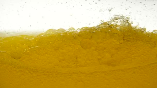 Close-up view of olive oil for food is mixed with water. Different density of the liquid, fat molecules do not mix with water. Focus boiling oil. Vegetable oil in a container on a white background. — Αρχείο Βίντεο
