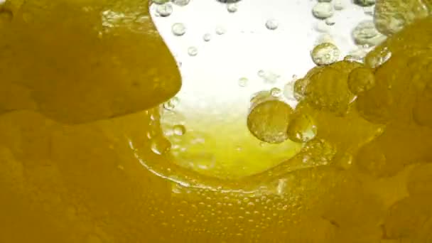 小さじ1杯で防がれた亜麻仁油の動きの背景。黒いクミン油は水と混合せず、白い背景、クローズアップビューに対して空気の泡構造を作成します。. — ストック動画
