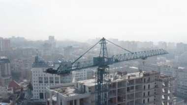 Bir vincin uzaktan çekilmiş görüntüsü ve şehir merkezindeki çok katlı bir ofis binasının yapımı. Kışın modern konut binaları ve gökdelenleri ile şehrin aktif gelişimi.