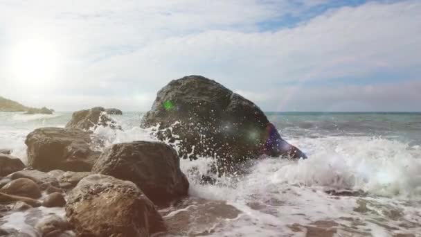 Close-up shooting of sea waves crashing on large coastal stones, Crimea. A small storm in the sea leads the waves. Beautiful splash of ocean waves on rocks during the day in slow motion. — Stock Video