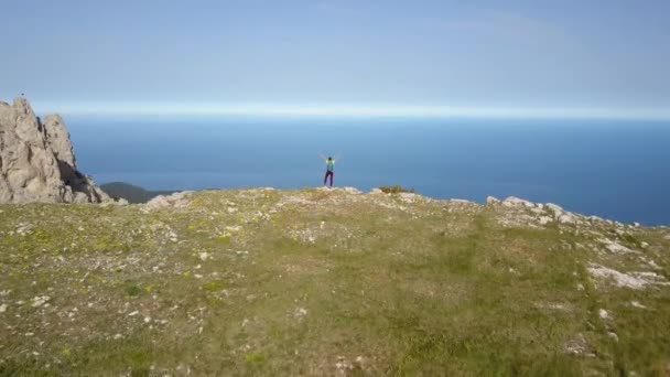 Aerial view of sports tourist girl with backpack stands on the edge of the famous Ai-Petri Mountain and enjoys a stunning panorama of the city of Alupka and the Black Sea, Crimea. Active healthy life — Stock Video