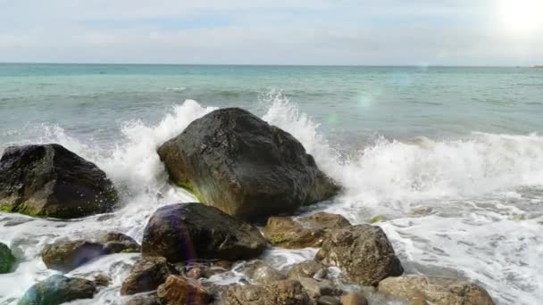 Bella spruzzata di una piccola onda marina sulle pietre. Onde del Mar Nero si schiantano alternativamente contro pietre in piedi in acqua salata al rallentatore, Crimea, Ucraina. Orizzonte dell'oceano e del cielo . — Video Stock