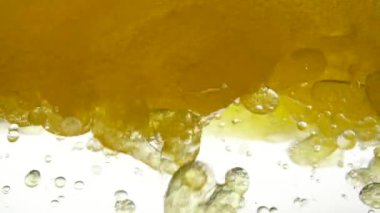 Close-up view of bio fuel shot in a research laboratory. Focus of boiling yellow oil is widespread, the bubble texture is a full frame and a macro of many different droplets. Golden fluid with bulbs.