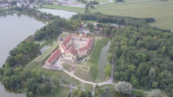 Meisterwerk der Architektur in Weißrussland - Schloss Neswisch inmitten von Seen und Parks, von oben gesehen. Flug über die berühmte und historische Burg Nosvizh bei warmem, sonnigem Wetter in der Altstadt von Nesvizh, Weißrussland. — Stockvideo