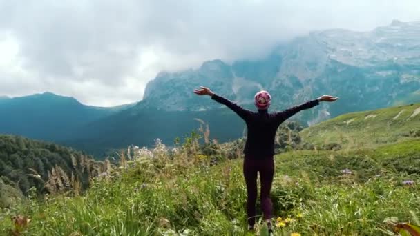 Un acercamiento y rodaje lejano de una turista que llega al borde de la montaña y admira el hermoso paisaje de otras montañas y la naturaleza del Cáucaso en el fresco otoño . — Vídeos de Stock