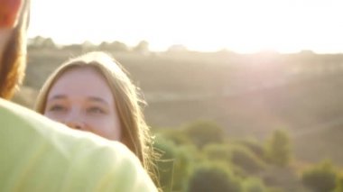 A young bearded guy kisses his sweetheart in a deserted meadow on a warm autumn day. Close-up view of a young couple kissing in a field with spikelets under the sun, focusing on the girls face.