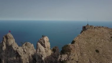 Coming shot of the amazing landscape of the highest mountain Ai-Petri and the Black Sea, Crimea, Ukraine. Top view of tourists walking on extreme bridge upstairs. Stepping over the abyss, top view.