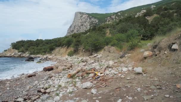 Nahaufnahme einer Mülldeponie am Schwarzen Meer. Das globale Problem der Menschheit ist die Einleitung von Müll und Umweltverschmutzung auf den Planeten. Verstopfter Teil des Ufers vor der Bergkulisse. — Stockvideo