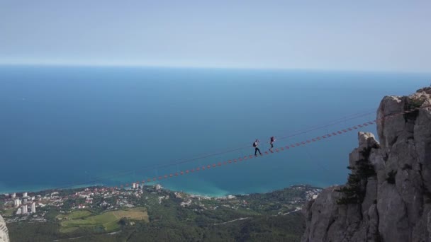クリミア半島で最も高い山のトップビュー 愛ペトリといくつかの観光客は黒海 ウクライナを背景に美しい山の頂上に極端な橋の上にハイキングを登る — ストック動画