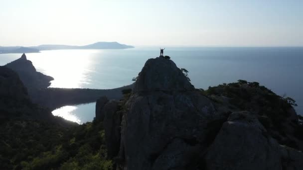 Pareja motivada de turistas hombre y mujer conquistaron una hermosa montaña en la Crimea llamada Karaul-Oba. Increíble vista aérea del sol naciente sobre las montañas y el Mar Negro en otoño — Vídeo de stock