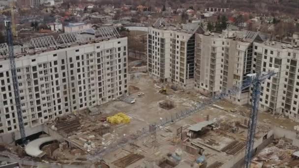 Vista superior do edifício de vários andares atualmente em construção na cidade de Kharkov, Ucrânia. Tiro aéreo de um edifício alto e canteiro de obras. Guindastes para a construção de um edifício — Vídeo de Stock