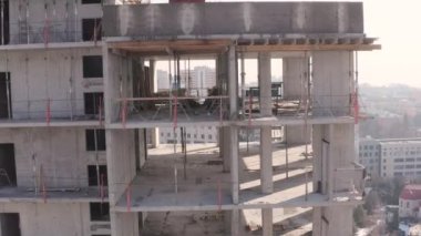 Şehirde yeni, modern, yüksek binalar inşa etme süreci. Tamamlanmamış bina yapısının boş katlarından yandan görüntüler. İnşaatçılar apartmanda duruyorlar..